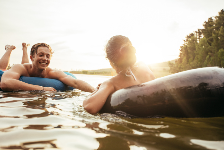 Affectionate young couple floating on inner tubes in water. Young man and woman in an inflatable tube in a lake on a sunny day.